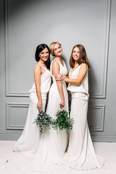 istock Bridesmaids in elegant white dresses in the studio 1284003606