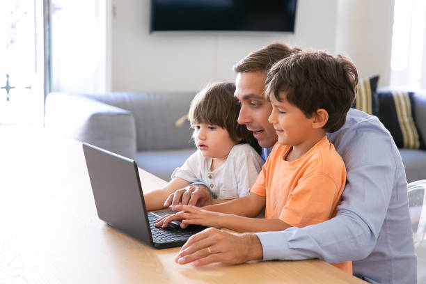 istock Exited father showing something on laptop to little sons 1284008342