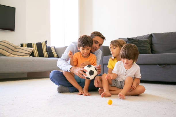 istock Focused dad holding ball and talking with children 1284011814