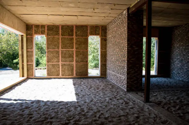 Photo of Construction of houses. The walls are made of straw, the internal partitions are made of bricks, the ceiling is made of blocks covered with clay, metal supports.