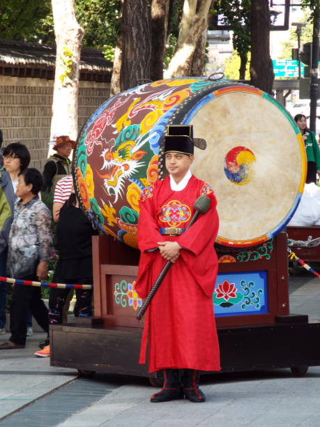 Seoul, South Korea, October 6, 2016: A man in front of a large drum at the Changing of the Royal Guard ceremony at the main entrance to Deoksugung Palace in Seoul