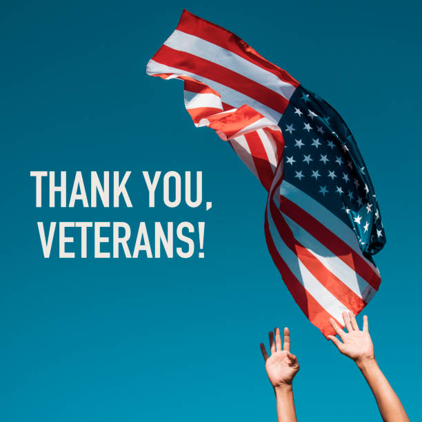 american flag and text thank you veterans the text thank you veterans and a young caucasian man launching a flag of the United States to the blue sky, or about to catch it as it flights in the air veterans day stock pictures, royalty-free photos & images