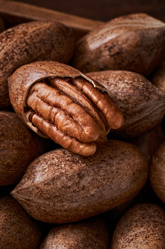 Close-up of open Pecan nut halves coming out from a wooden serving scoop