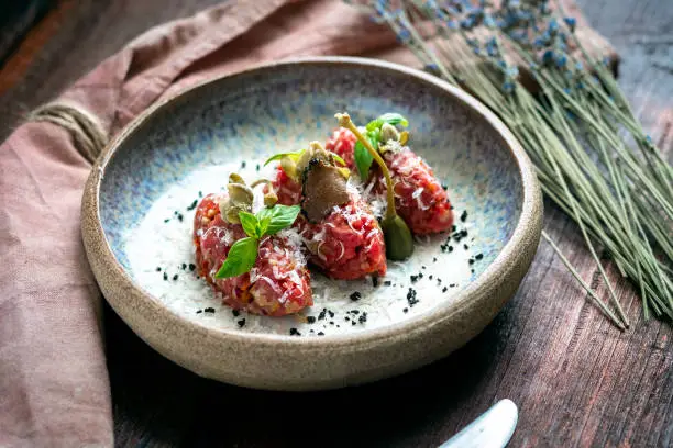 Beef tartare with mushrooms, truffle and capers on a plate. Serving in the restaurant, Haute cuisine