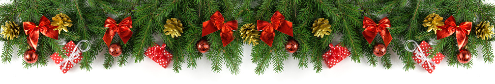 Very wide Christmas border with fir branches, Golden cones, red bows and balloons and other decorations isolated on white.