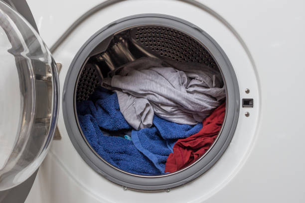 istock Open door in white washing machine with laundry inside. 1284023494
