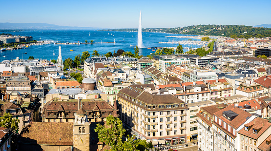 Geneva, Switzerland - September 4, 2020: Panoramic view over the rooftops of the city, the bay of Geneva and the Lake Geneva from the bell tower of Saint-Pierre cathedral on a sunny summer day.