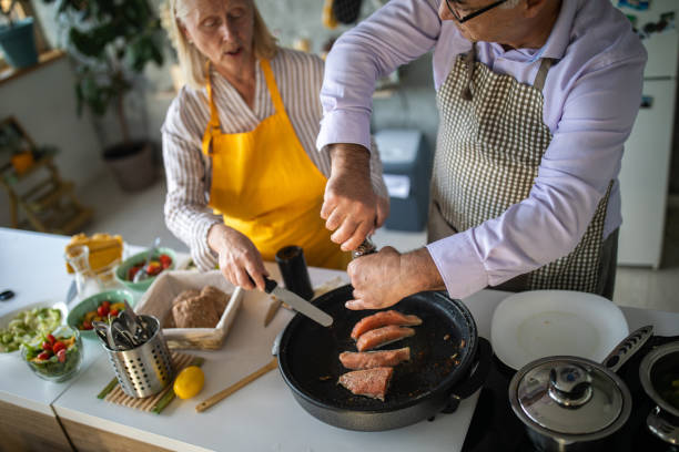 istock Senior man seasoning fish while preparing lunch with his wife in kitchen 1284025936