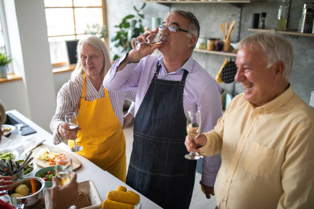 istock Senior friends enjoying wine while they preparing vegetarian lunch at home 1284025939