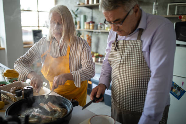 istock Senior couple preparing fish in electric cooker 1284026168