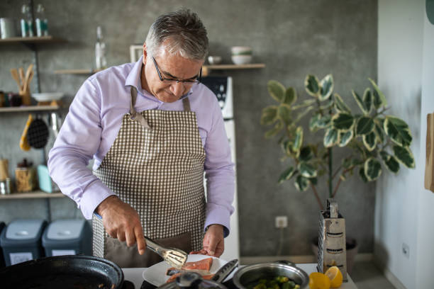 istock Senior man preparing fish at home 1284027090