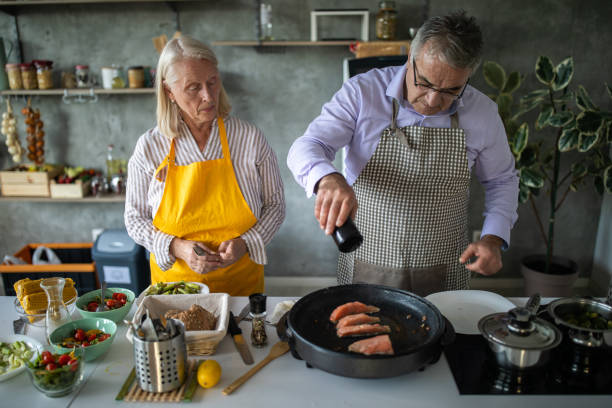 istock Senior couple preparing fish for lunch in kitchen at home 1284027159