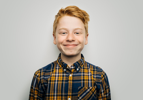 Portrait of cute happy boy with redhead. Smiling male child is wearing patterned shirt. He is against white background.