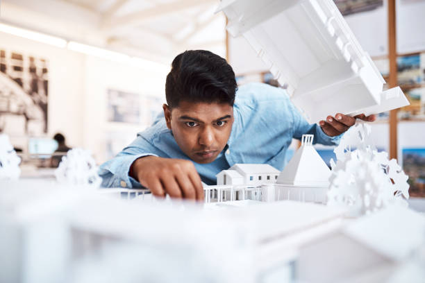 The better the quality, the higher the customer satisfaction Shot of a young architect designing a building model in a modern office architectural model stock pictures, royalty-free photos & images