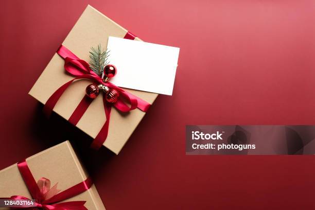 Carton Gift Box Decorated Red Ribbon Bow And Blank Paper Card Mockup On Marsala Red Background Flat Lay Top View Christmas Gift New Year Present Concept Stock Photo - Download Image Now