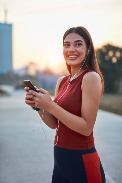 istock Modern young woman with cellphone making pause during jogging / exercise. 1284031230