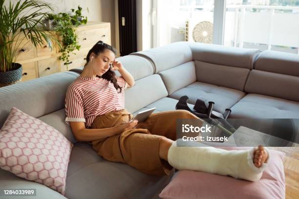 Sad Young Woman With Broken Leg At Home Stock Photo - Download Image Now - Broken Leg, Orthopedic Cast, People