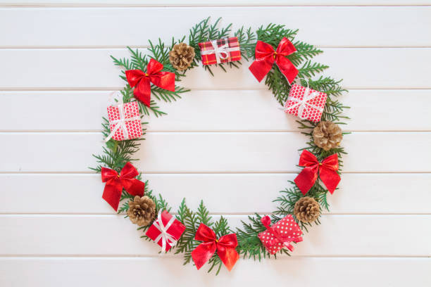 istock Christmas wreath, vintage composition with green branches, pine cones, red ribbons and gift boxes on a white wooden background. Christmas, winter, new year concept. Flatlay, top view, copy space 1284035265