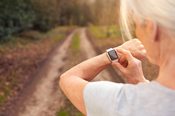 Close Up Of Senior Woman Running In Countryside Exercising Checking Smart Watch Fitness Activity App Close Up Of Senior Woman Running In Countryside Exercising Checking Smart Watch Fitness Activity App fitness tracker photos stock pictures, royalty-free photos & images