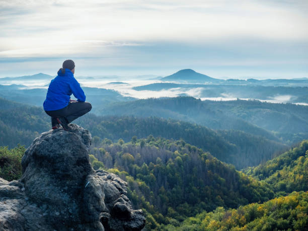 Hiker sit on cliff and looking beautiful landscape. stock photo
