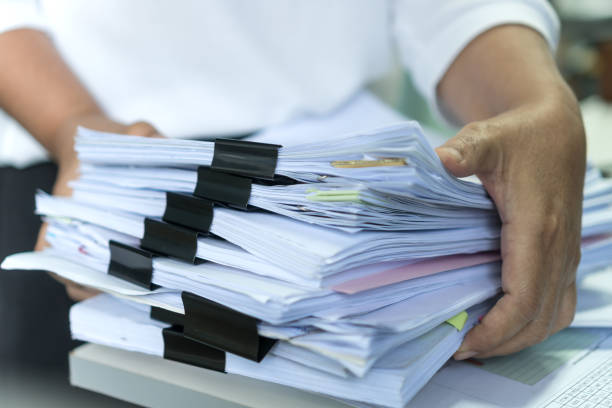 istock Employee checking business unfinished documents with stacks paper files and managing document achieves preparing meeting planing at busy work in financial office. Tax time in filing information 1284038364