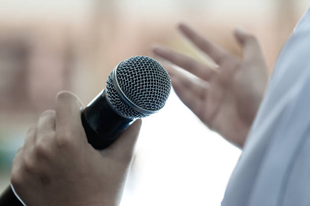 istock Smart businessman speaker speech with microphone at seminar conference and speaking with mic in auditorium room while explaining or gesturing in event light convention hall Background 1284038379