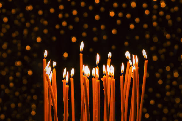istock Thin yellow candles burning on the black background with glitter lights 1284038386