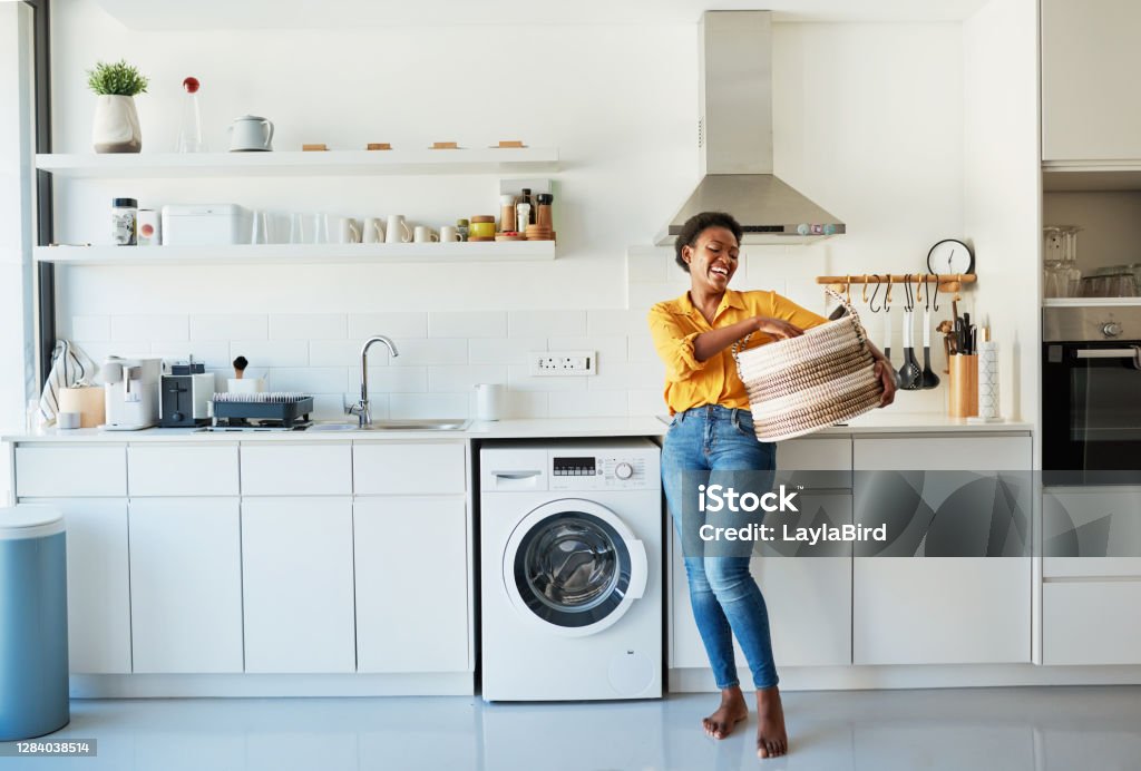 My favourite chore is doing the laundry! Shot of a young woman doing her laundry at home Cleaning Stock Photo