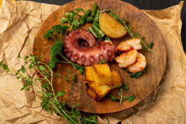 istock Grilled octopus tentacle on a wooden plate served with shrimps 1284038708