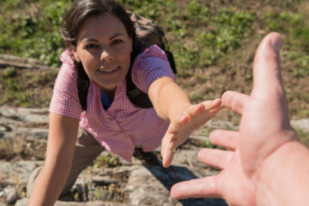 Female Rock Climber Reaching for Helping Hand stock photo
