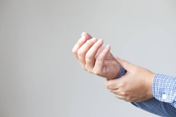 Image of a businessman holding a wrist because of exhaustion from work stock photo