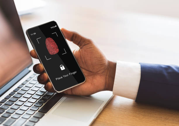 Man holding phone with fingerprint scanning smartphone app Biometric Identification Concept. African American Man Holding Cellphone In Hand, Showing Application For Fingerprint Scanning With A Zone To Touch With Thumbprint Icon On The Device Screen biometric security stock pictures, royalty-free photos & images