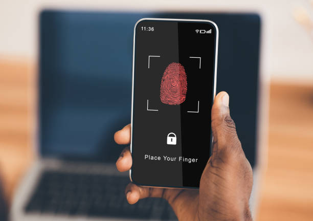 istock Black man holding phone with fingerprint scanning app 1284039957
