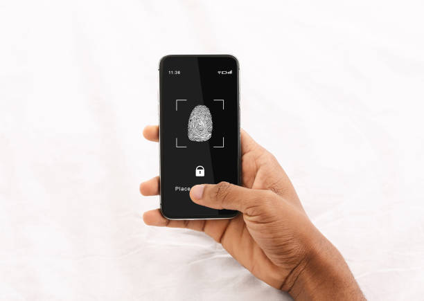 istock Black man holding phone with fingerprint scanning app 1284039962