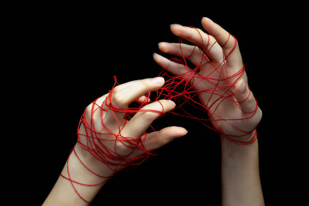 istock Two female hands entangled in a network of red social media threads on a black isolated background.Selective focus.The concept of social networks, social dependence. 1284040065