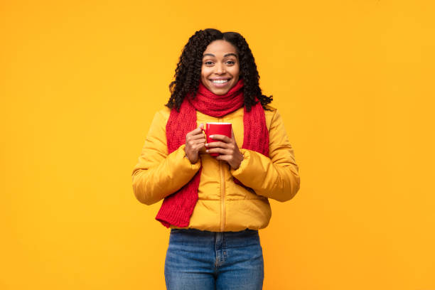 istock Black Woman In Winter Jacket Holding Coffee Cup, Yellow Background 1284040547