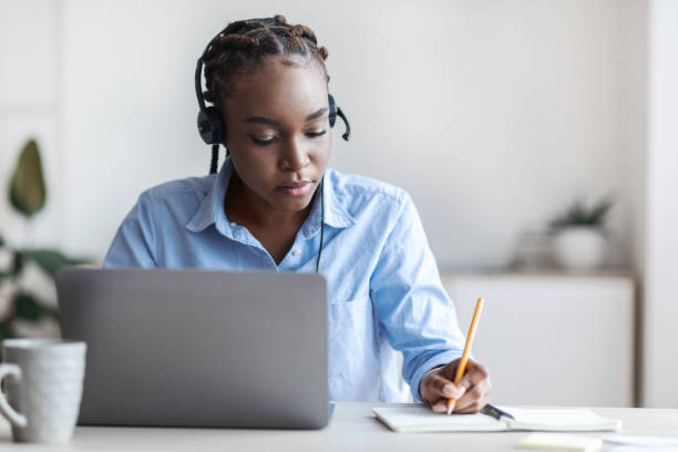 istock Online Training. Black female employee watching webinar on laptop and taking notes 1284041680