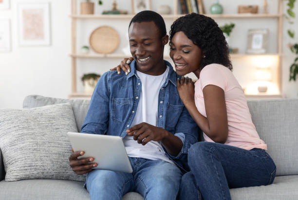 istock Joyful black family using digital tablet in living room 1284041749