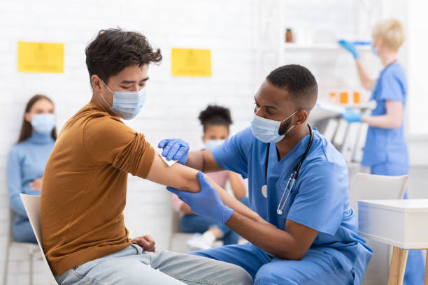 paciente masculino asiático vacunarse contra coronavirus en el hospital - asistente sanitario fotos fotografías e imágenes de stock