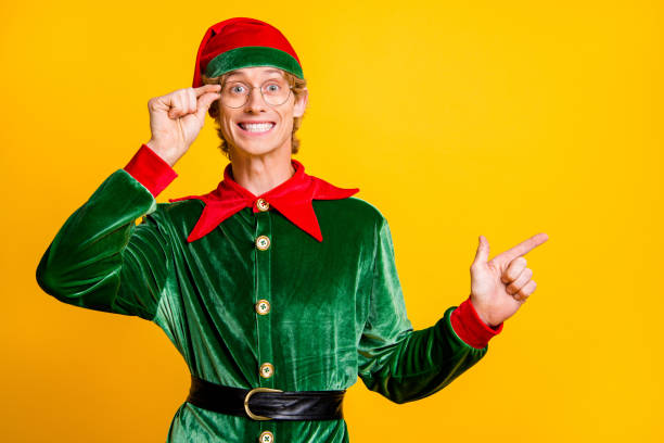 istock Portrait of his he nice attractive cheerful cheery funny guy elf demonstrating copy empty blank place space Eve Noel December isolated over bright vivid shine vibrant yellow color background 1284042695