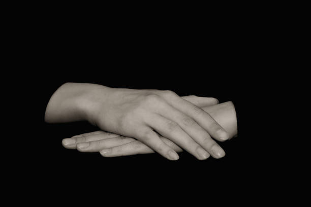 istock Female hands on a black background lie palms down on a dark table. Isolated background, copy space, tinting for vintage photos. The concept of waiting. 1284042971