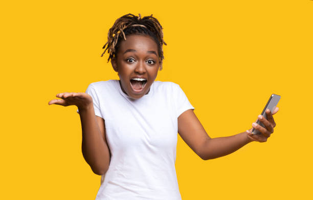 istock Shocked african american lady with smartphone on yellow 1284043799