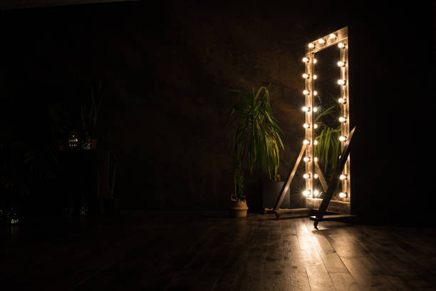 Toilet mirror stands on a wooden floor with light bulbs for lighting Toilet mirror stands on a wooden floor with light bulbs for lighting. Close-up. backstage stock pictures, royalty-free photos & images