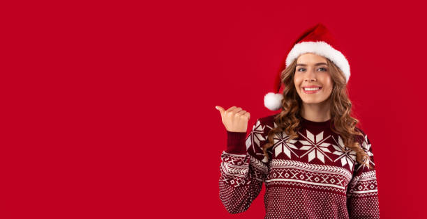 istock Christmas sale concept. Happy young woman pointing at empty space on red studio background, panorama 1284043893