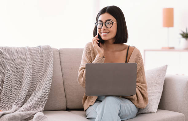 istock Portrait of smiling woman using pc talking on cellphone 1284043922