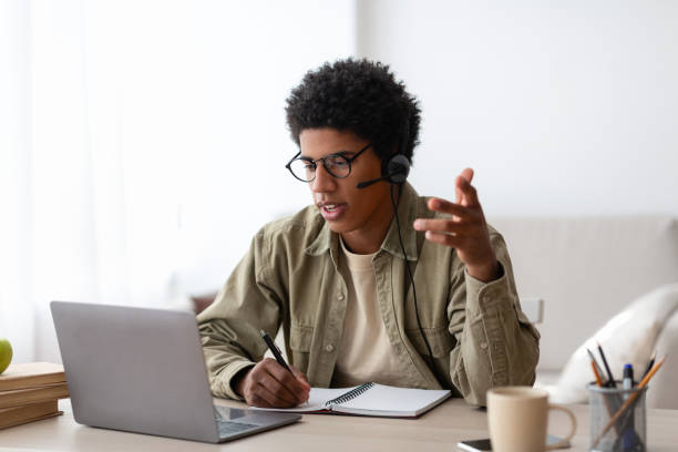 istock Online communication and education concept. Serious black student talking to his teacher on laptop from home 1284049024