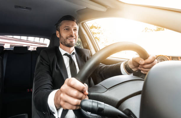 istock Happy rich businessman in suit driving car 1284049335