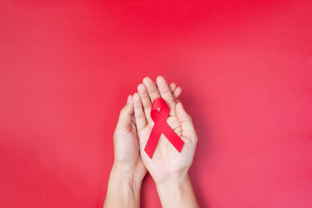 hand holding red ribbon for supporting people living and illness. healthcare and safe sex concept. december world aids day and multiple myeloma cancer awareness month - hiv imagens e fotografias de stock