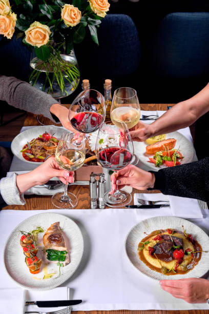 istock Four hands with glasses of wine over a table with food. 1284052721