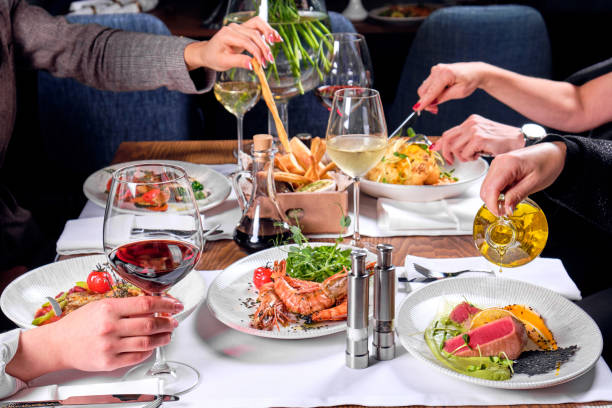 Hands of four people at a table with food. Hands of four people at a table with delicious food in a restaurant. actinopterygii stock pictures, royalty-free photos & images